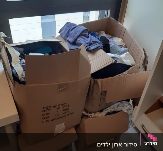 קופסאות קרטון מלאות בבגדים ליד חלון